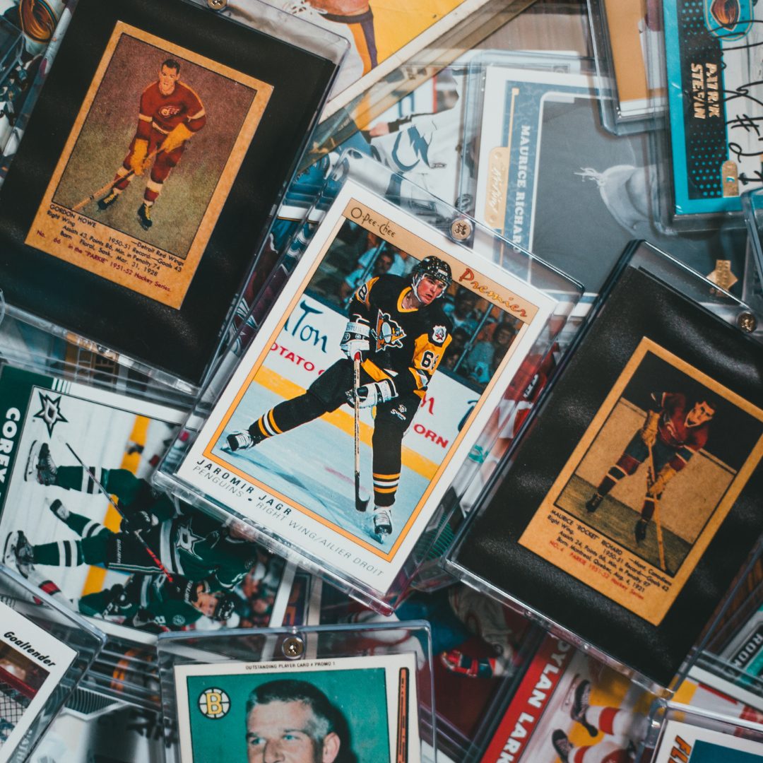 A scattered collection of vintage and modern hockey trading cards, including a prominent card of Jaromír Jágr in a Pittsburgh Penguins uniform, all encased in protective sleeves