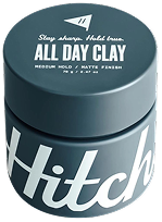 Dark-colored jar of "Hitch All Day Clay" hair product with bold white branding, featuring medium hold and matte finish