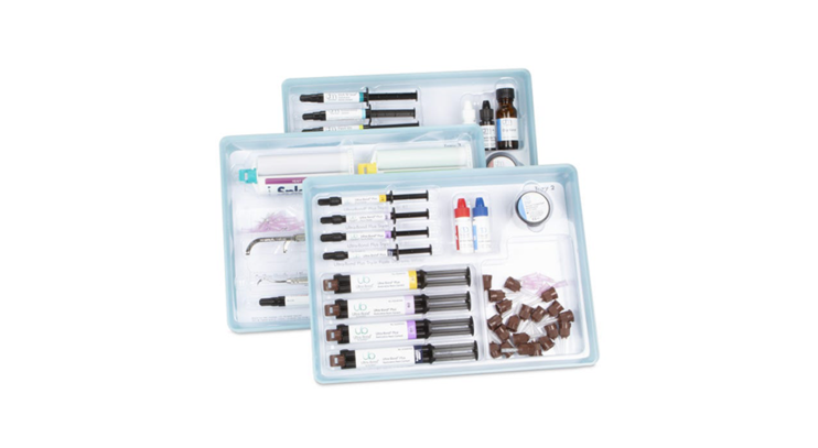 A dental composite kit with multiple syringes, applicator tips, bottles, and accessories neatly organized in three plastic trays