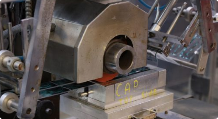 Close-up of a hot stamping machine applying foil to product packaging using a heated metal die and mechanical rollers