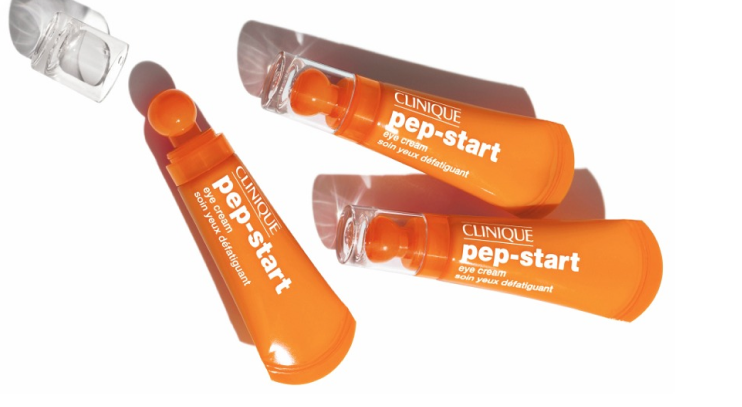 Three orange tubes of Clinique Pep-Start eye cream with rounded applicator tips, arranged on a white surface with shadows