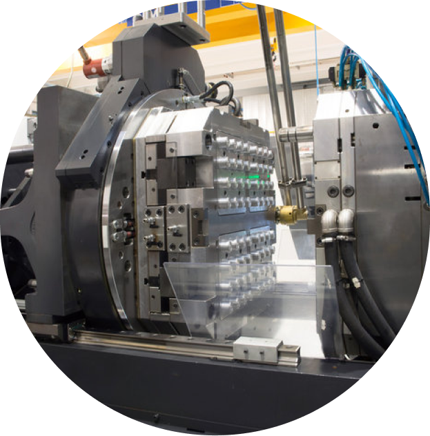 A large industrial injection molding machine with a multi-cavity metal mold open, revealing its complex internal structure
