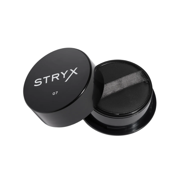 A black round compact container of STRYX makeup with the lid open, revealing a sponge applicator inside