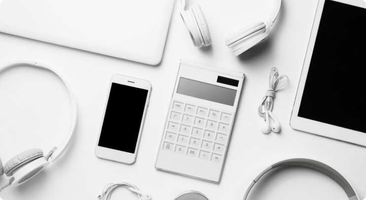 A flat lay of white electronic devices and accessories, including a smartphone, tablet, calculator, headphones, and earphones, all arranged on a white background