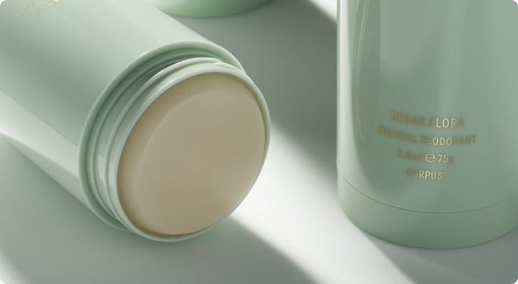 Close-up of mint green Corpus deodorant sticks, with one lying open to reveal the solid cream product inside