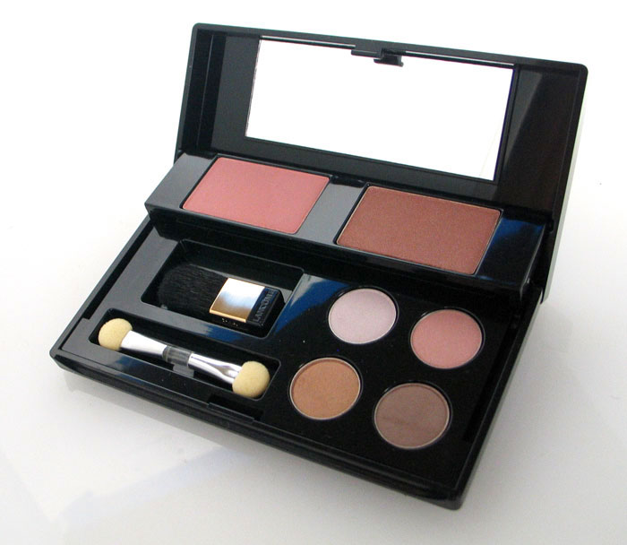 Open makeup palette containing blush, eyeshadows in neutral tones, a mirror, and two small applicator brushes