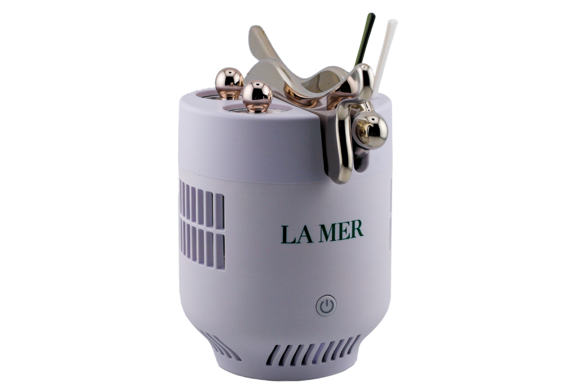 A white cylindrical La Mer skincare device with a power button and metallic massage tools attached on top, featuring ventilation slits on the sides