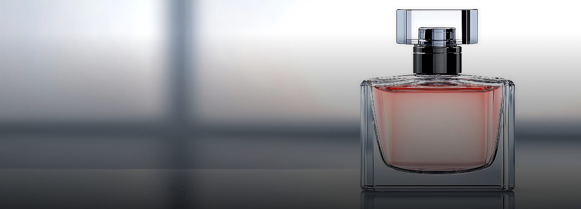 A rectangular glass perfume bottle with a soft pink liquid and a clear, square-shaped cap, set against a minimalistic blurred background